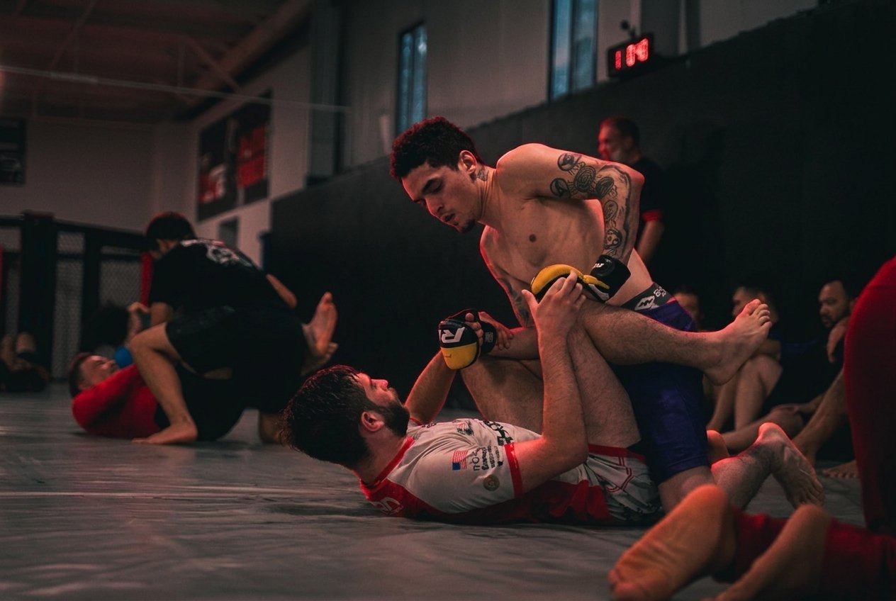 Live sparring round on the TRITAC mat, graded dark with red rim light