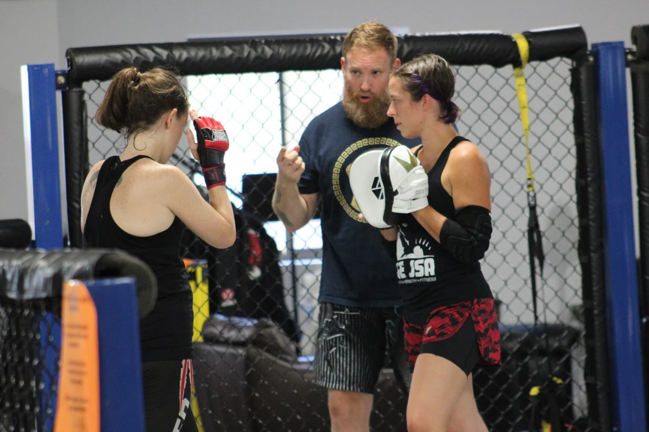 A coach guiding two students during practice
