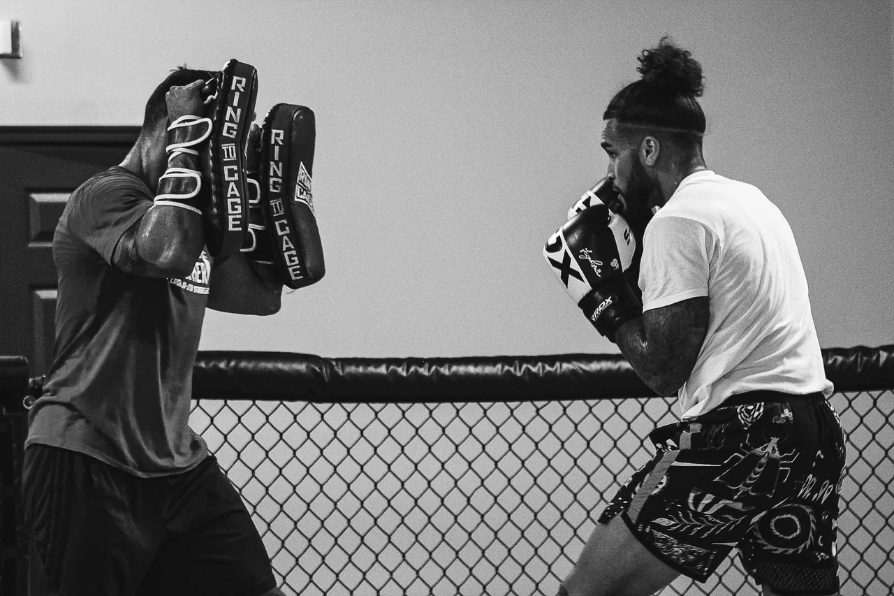 A student practicing with a coach on pads