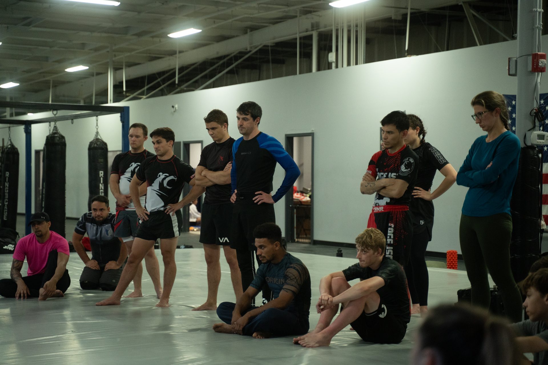 A class seated along the mat edge during instruction