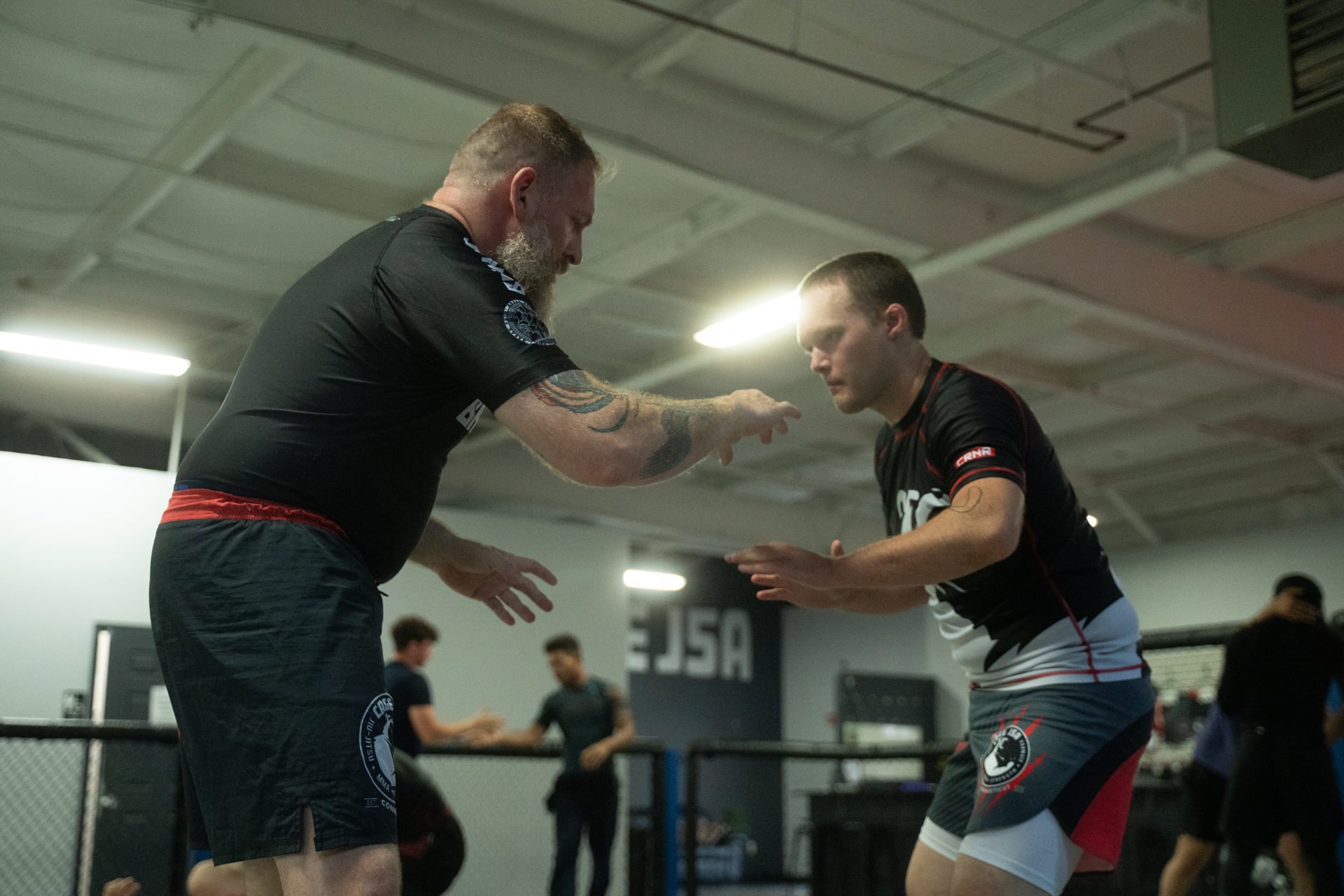 Two athletes hand-fighting for control, backlit on the mat