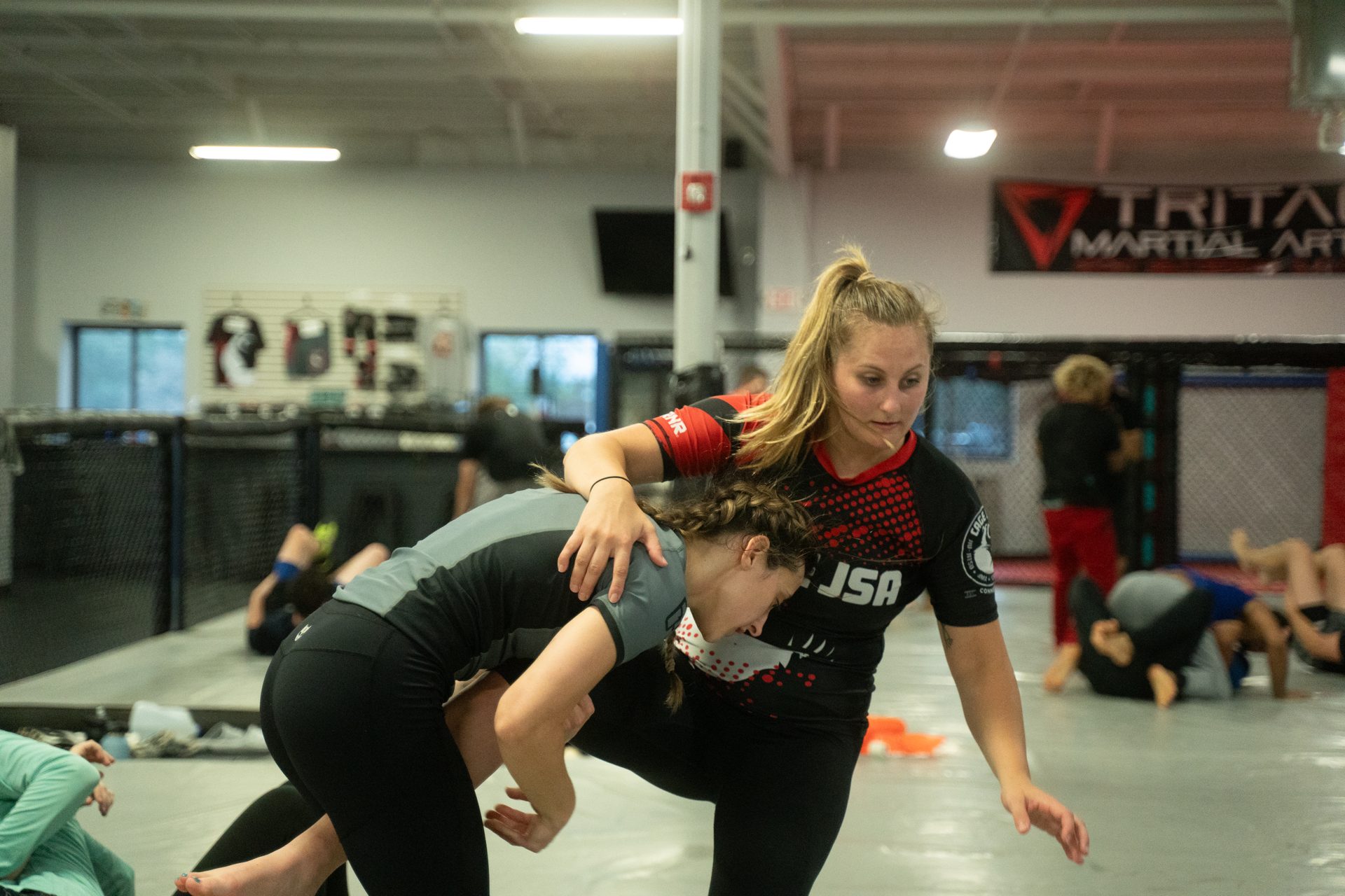 A standing exchange mid-snap-down on the TRITAC mat, class training behind