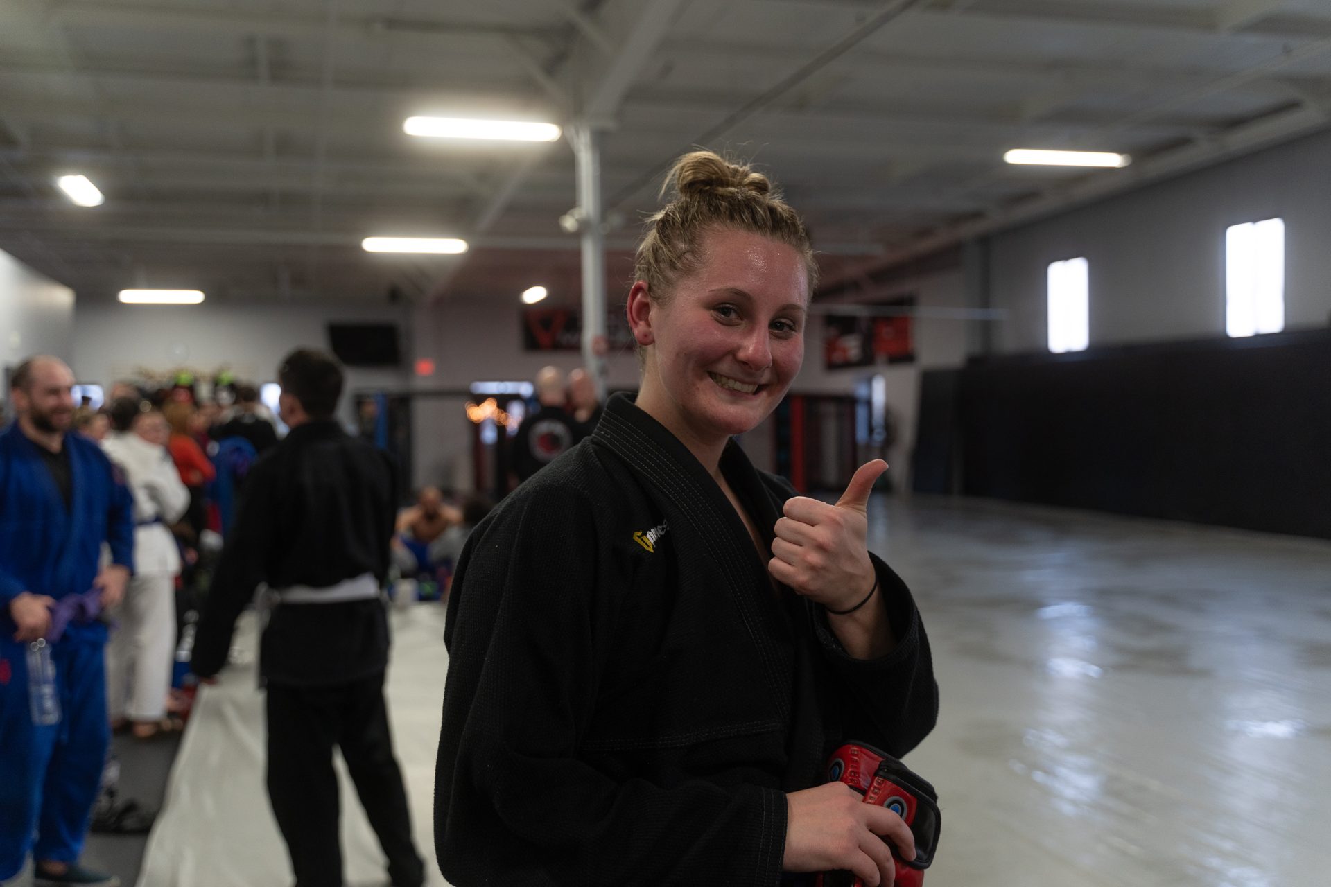 A member in a black gi giving a thumbs up and smiling