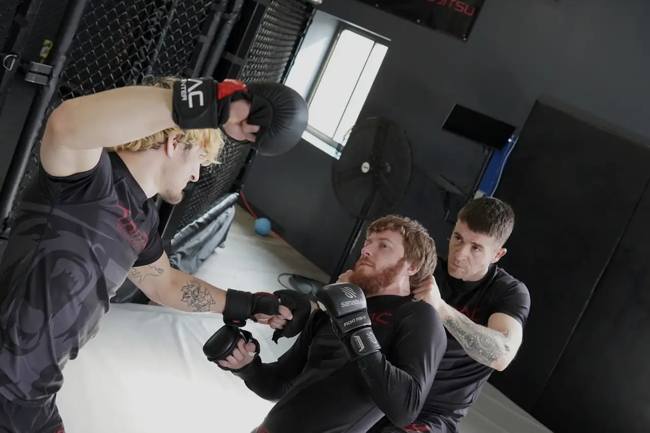 A defender covering up while two attackers grab and punch