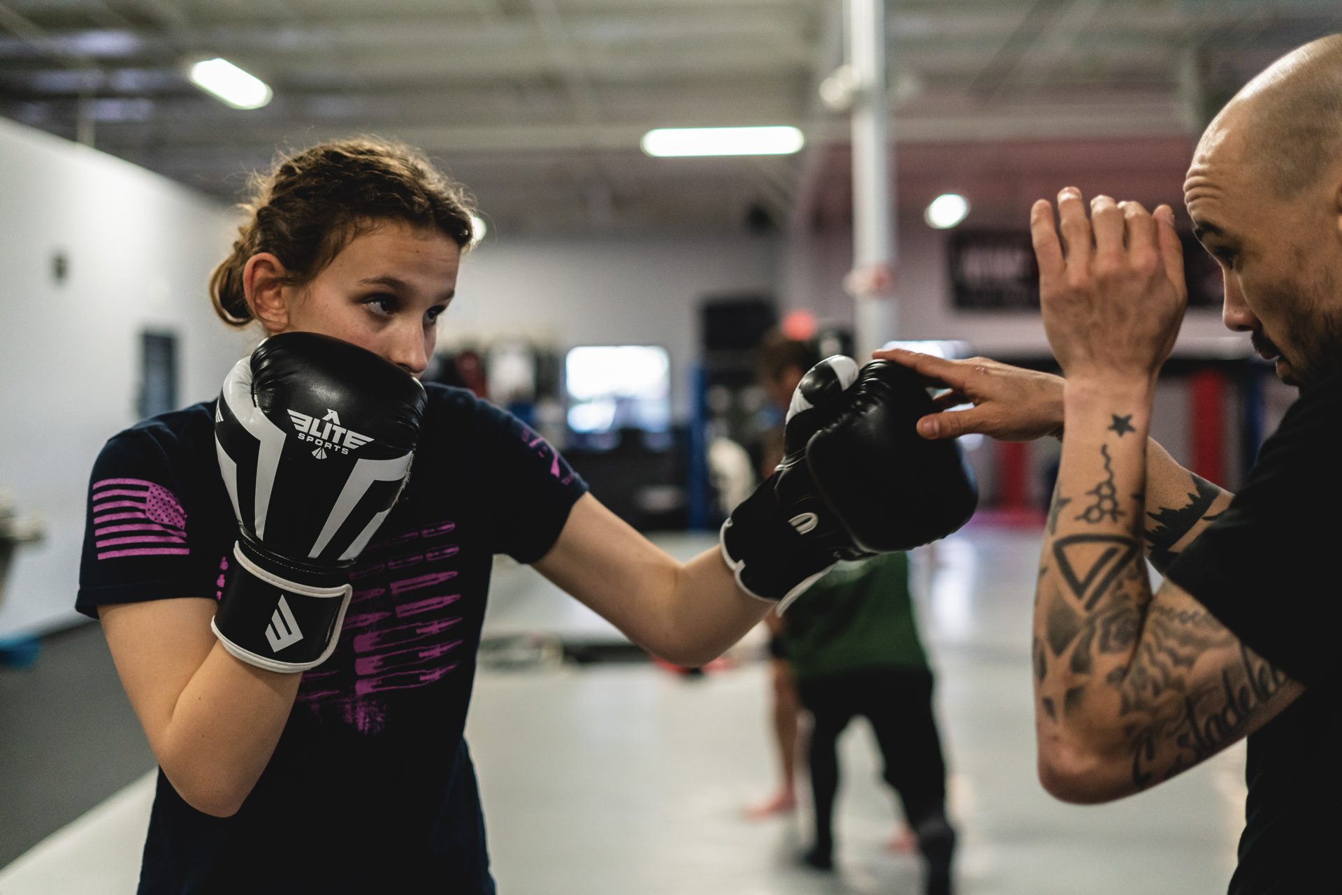 A coach correcting a student's guard during mitt work