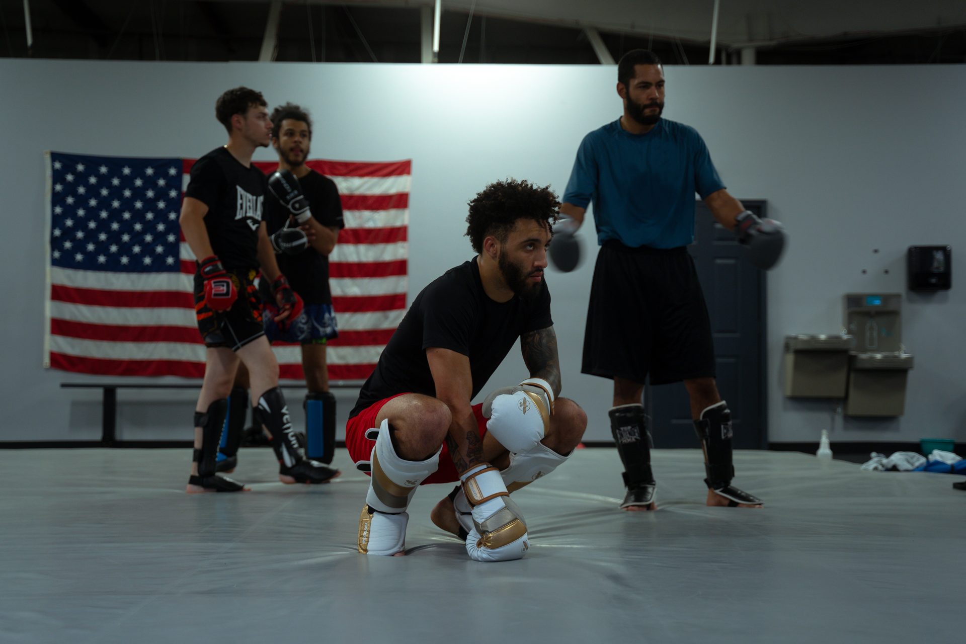 Fighter crouched and focused before a round, flag on the wall behind