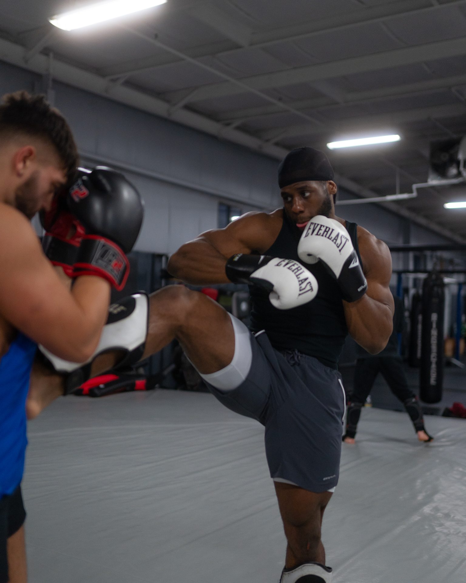 A striker checking a rising knee mid-exchange in the gym