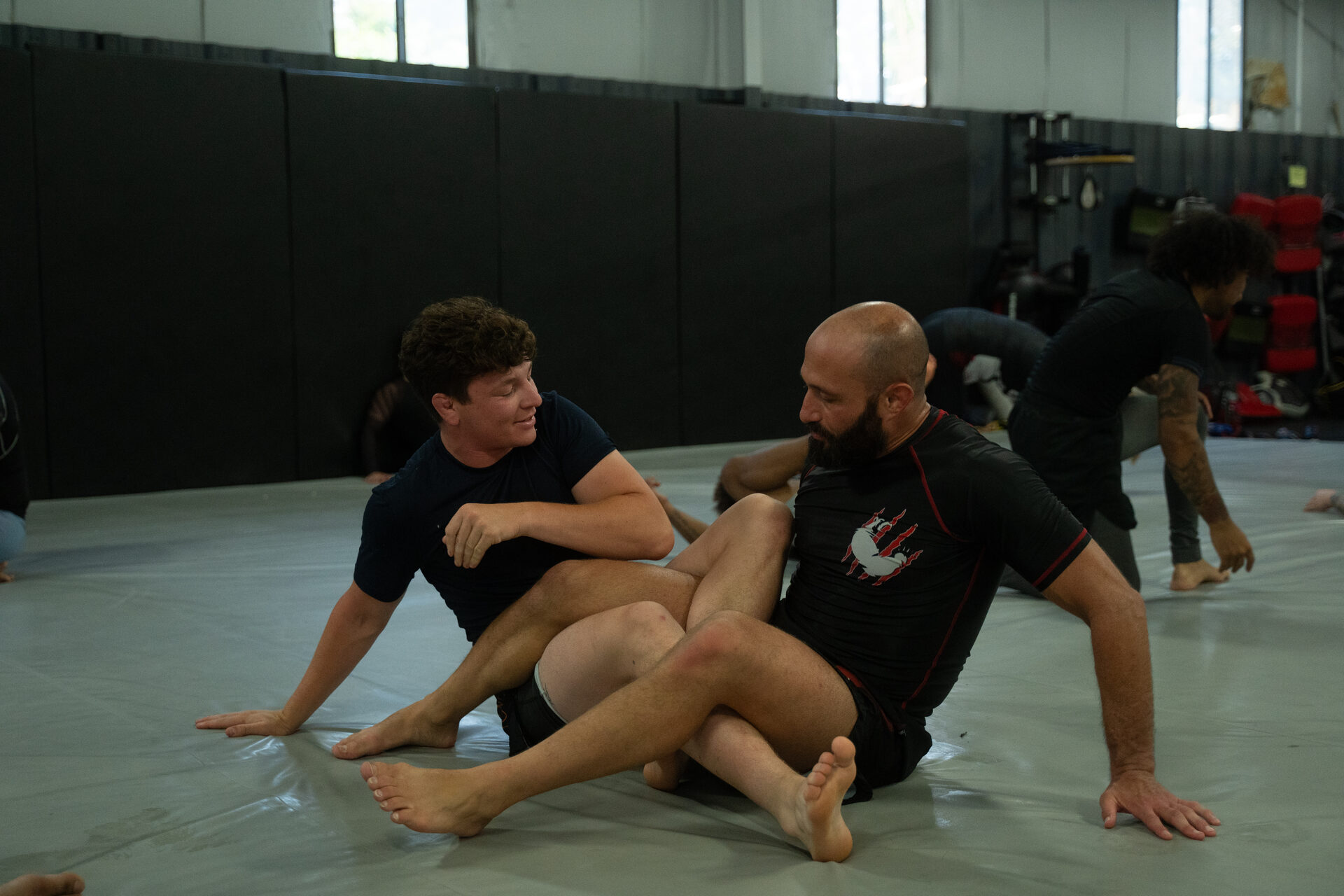 Pairs drilling on the mat with a coach standing over them