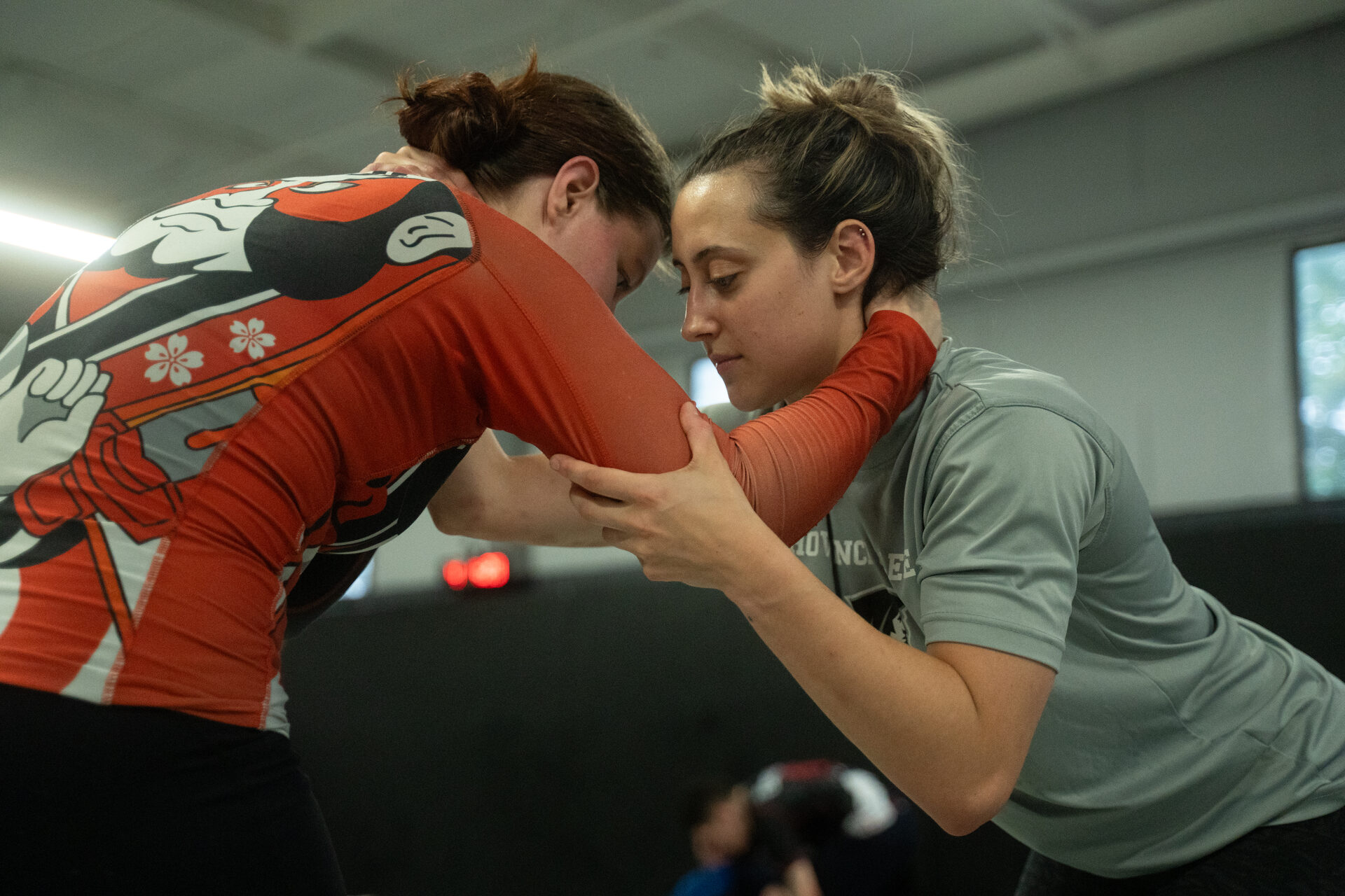 Two people locked in a tight standing clinch, heads together and hands on