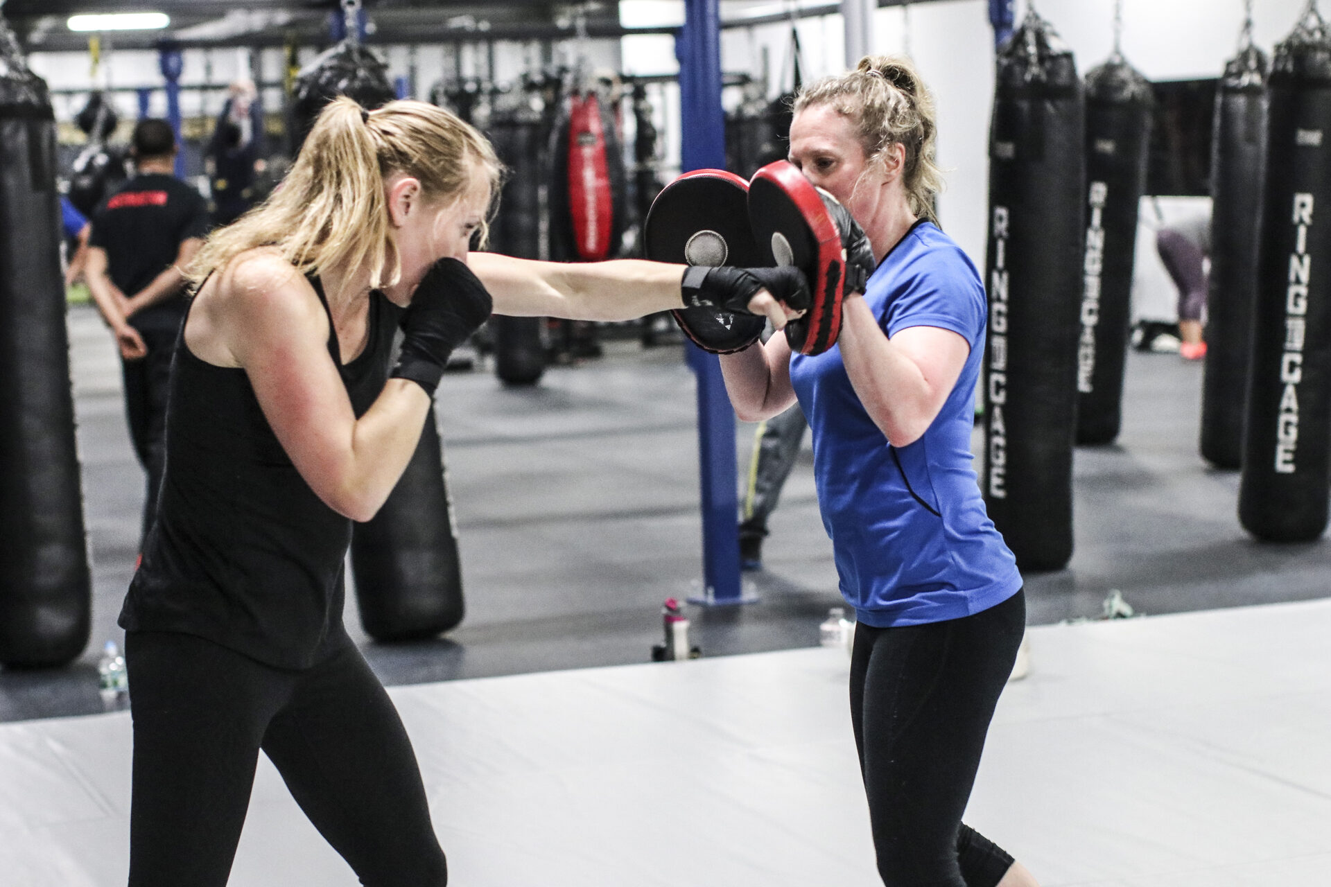A member driving a punch into focus mitts held by a partner in the bag row at TRITAC Training Center in Cromwell, CT