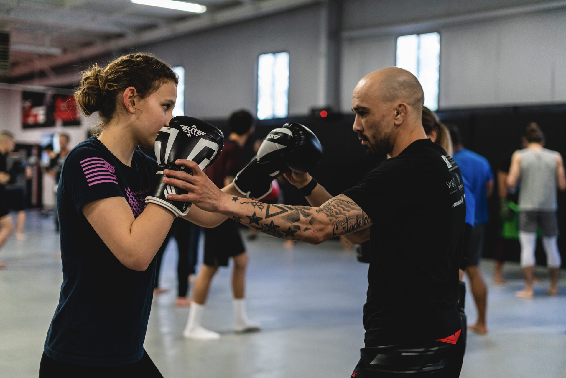 A coach holding focus mitts for one athlete on the mat at TRITAC Training Center in Cromwell, CT