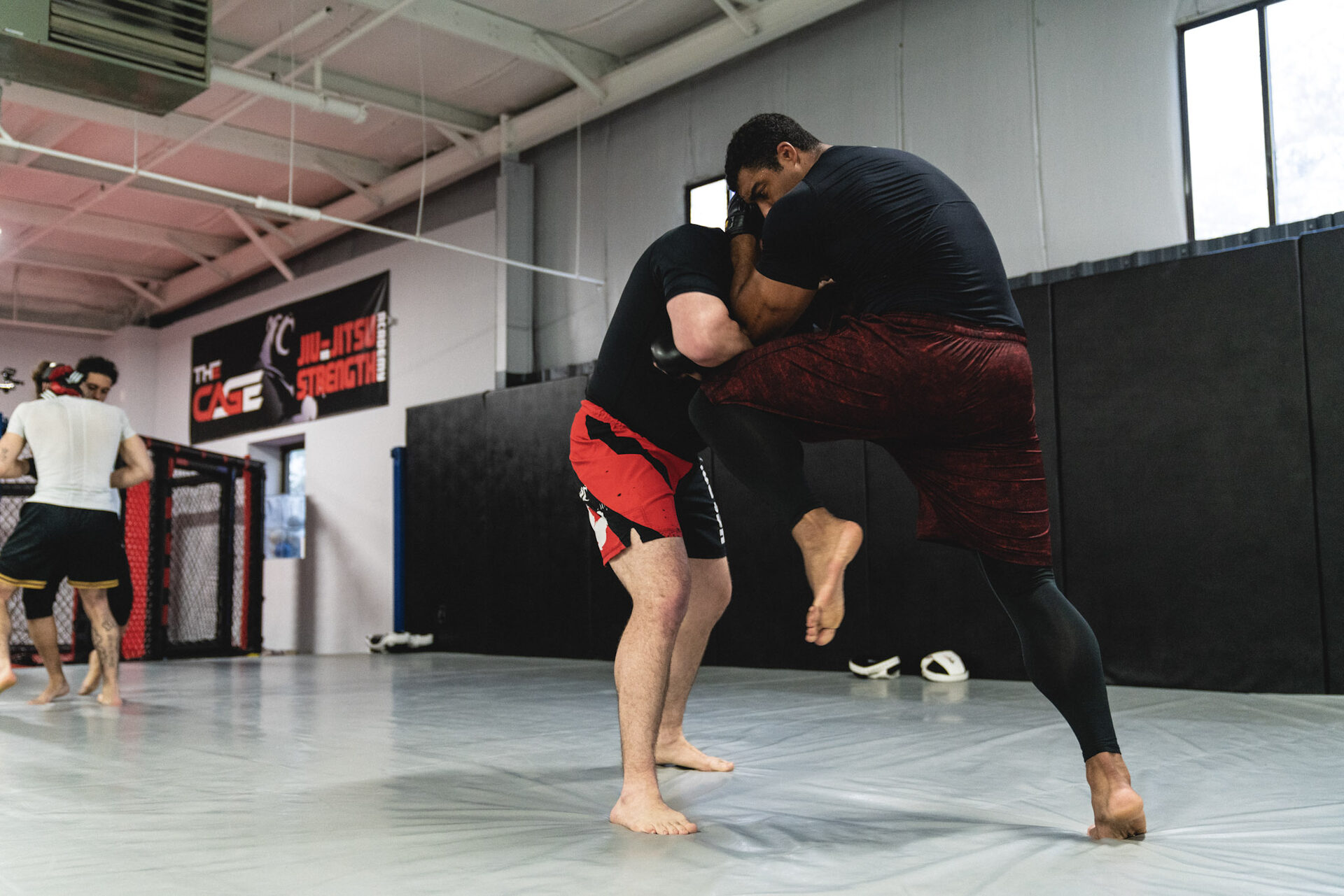 Two fighters in MMA shorts fighting for a standing takedown