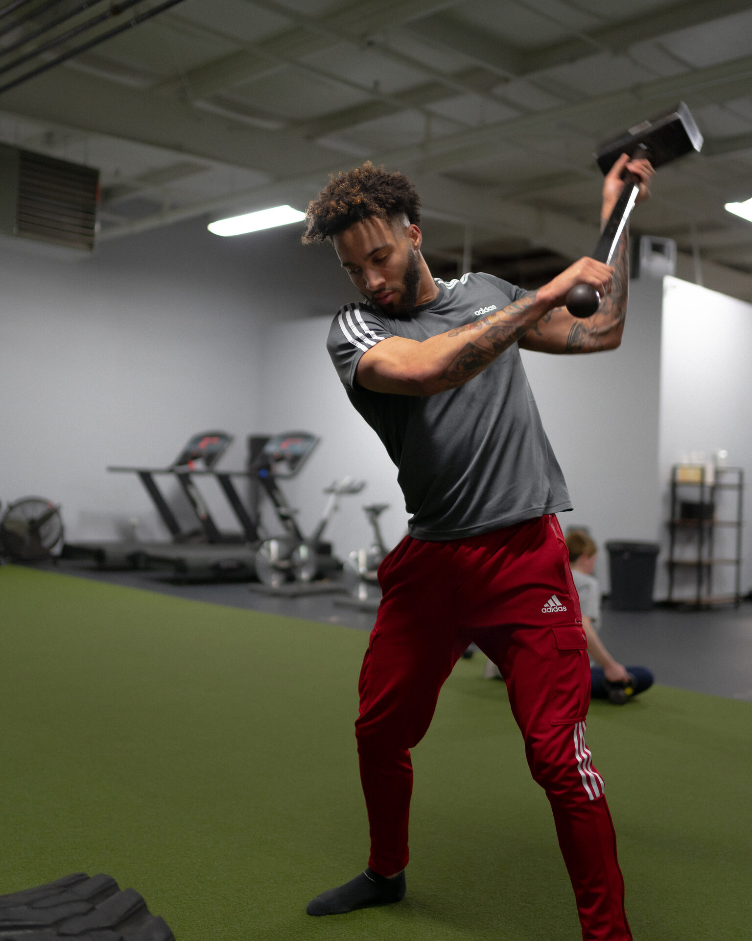 A member swinging a sledgehammer alone on the turf, no partner in the frame